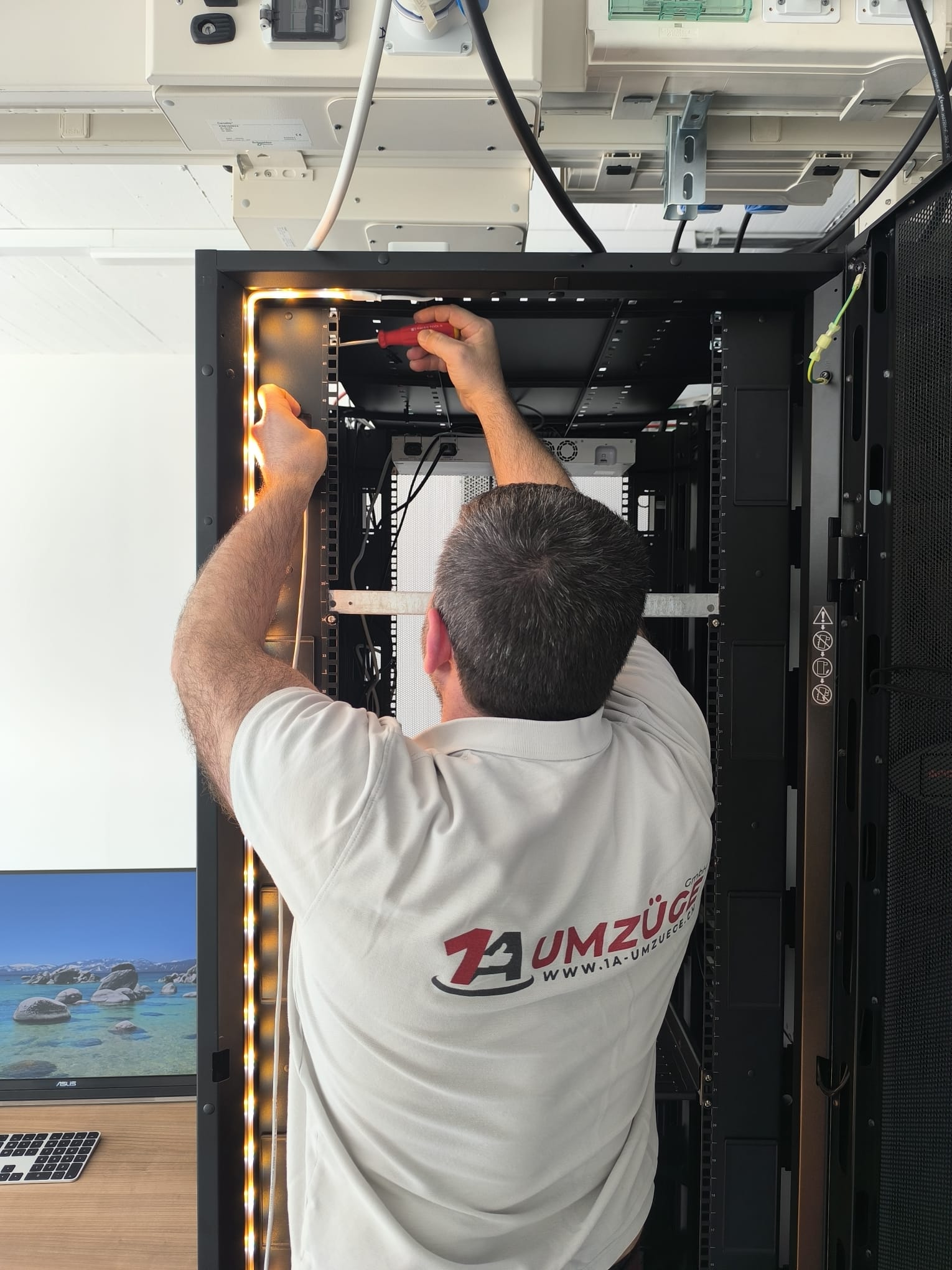 Ein Mitarbeiter arbeitet am oberen Rahmen eines geöffneten Serverschranks