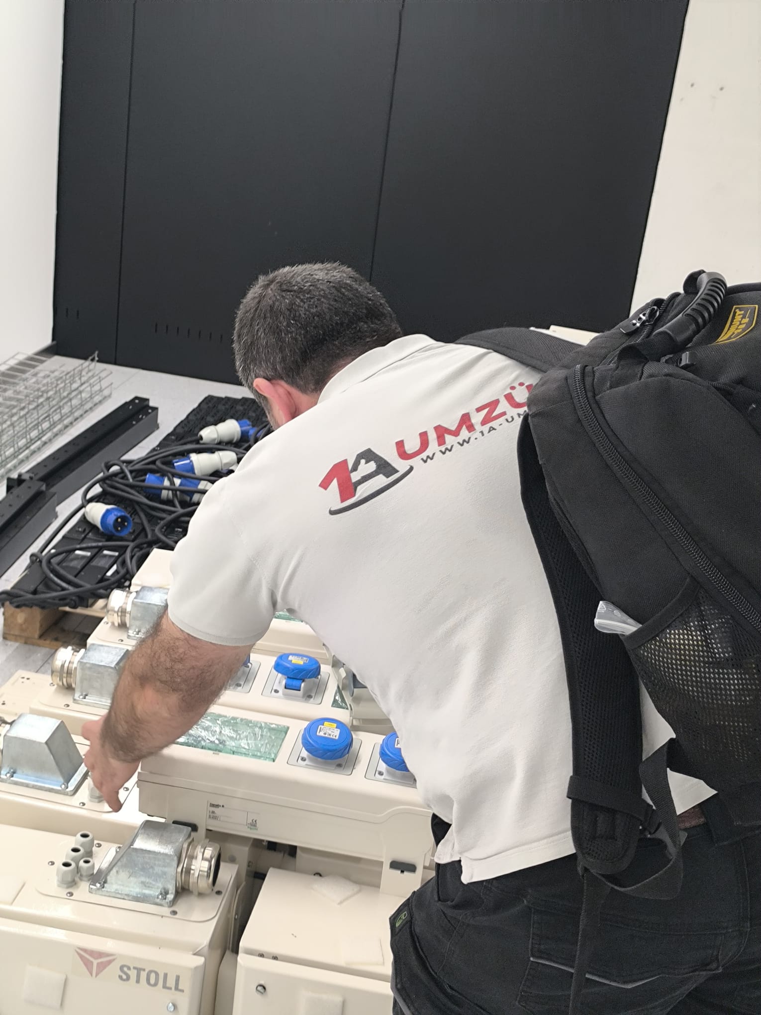 Ein Mitarbeiter bearbeitet ein ausgebautes technisches Bauteil vor einem Serverschrank