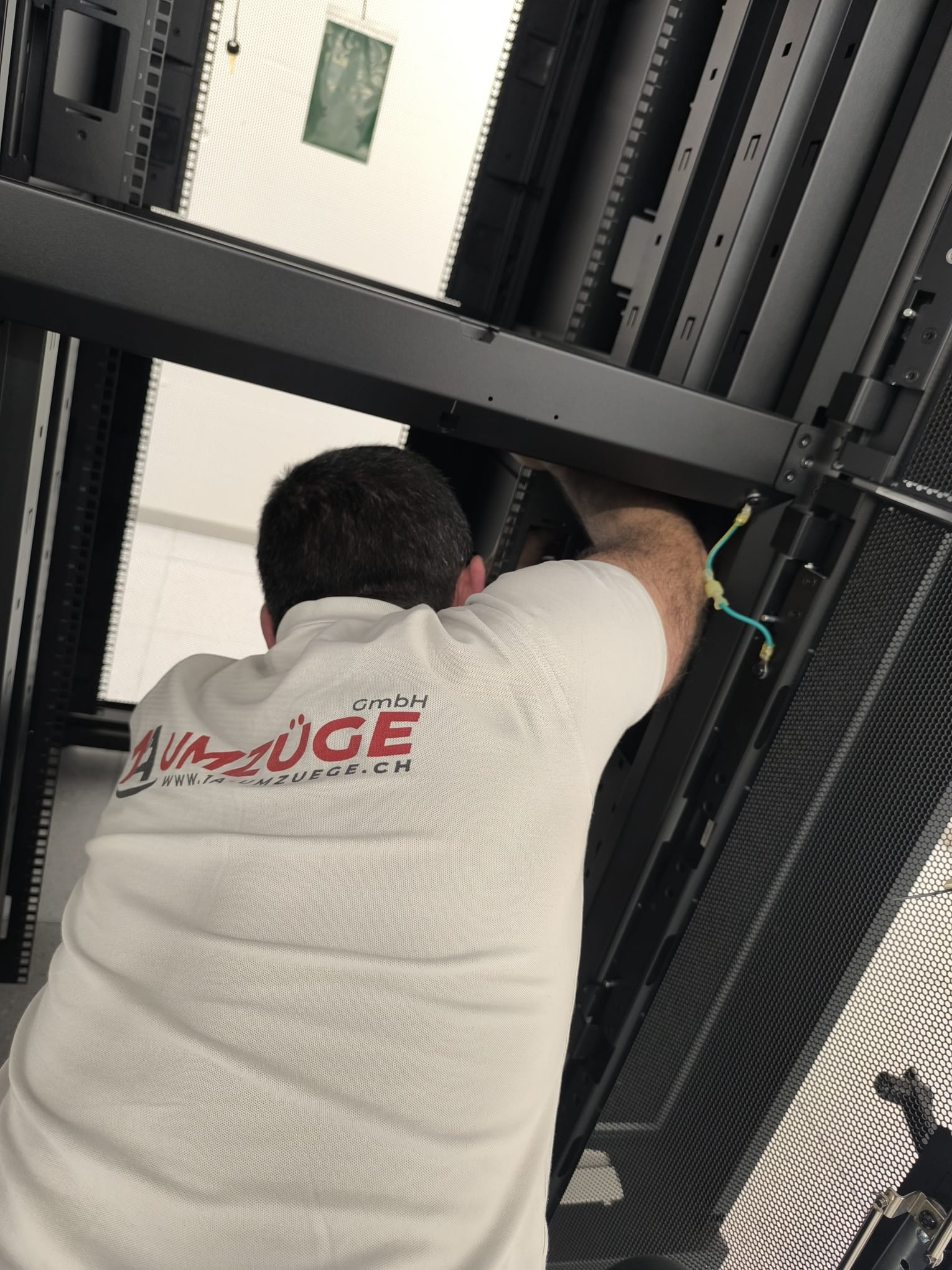 Ein Mitarbeiter arbeitet an einer Querstrebe im Inneren eines geöffneten Serverschranks